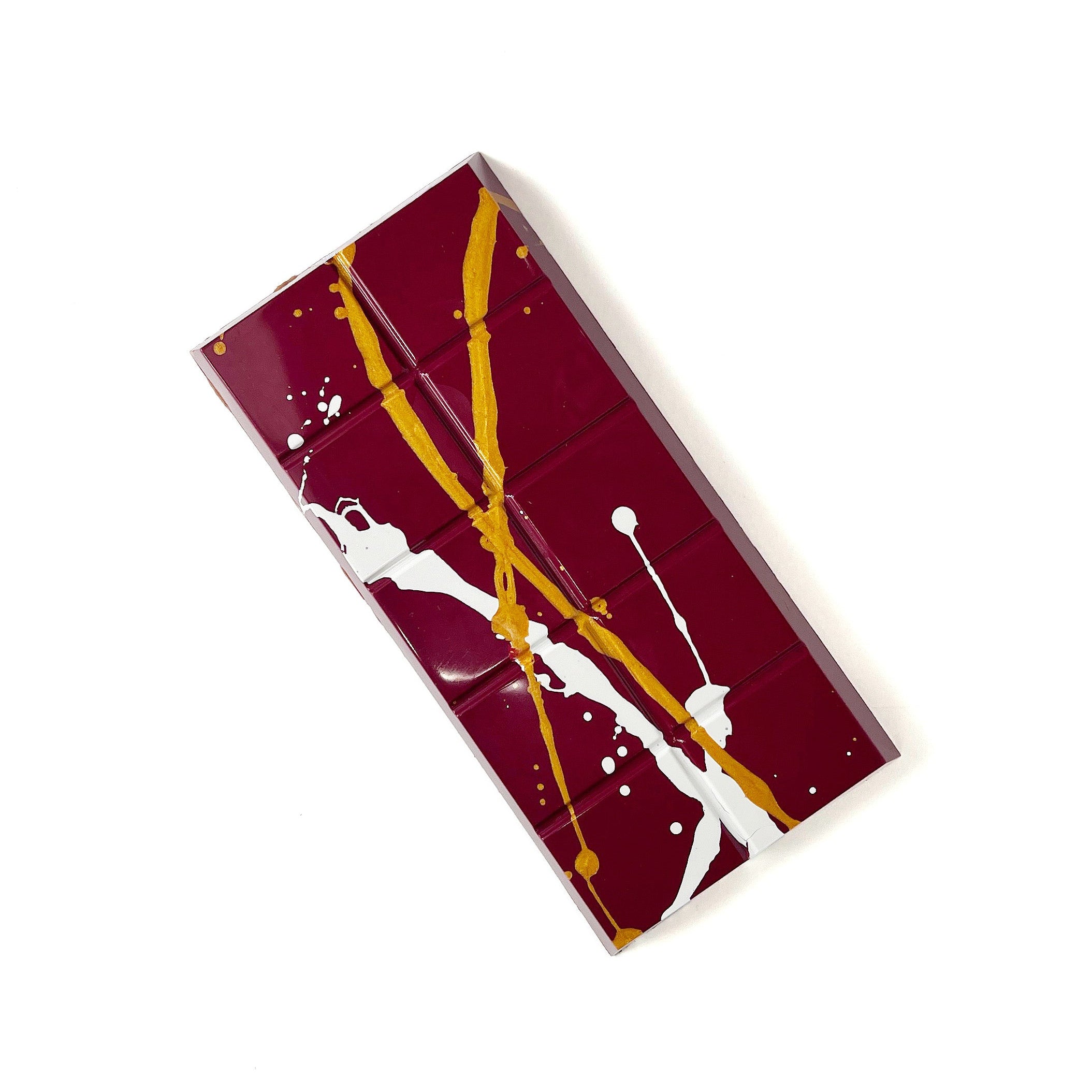 A chocolate bar with gold and white splashes on a white background