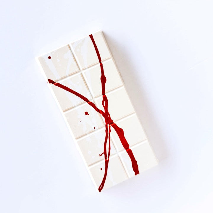 White bar of chocolate with bronze splatter on a white background