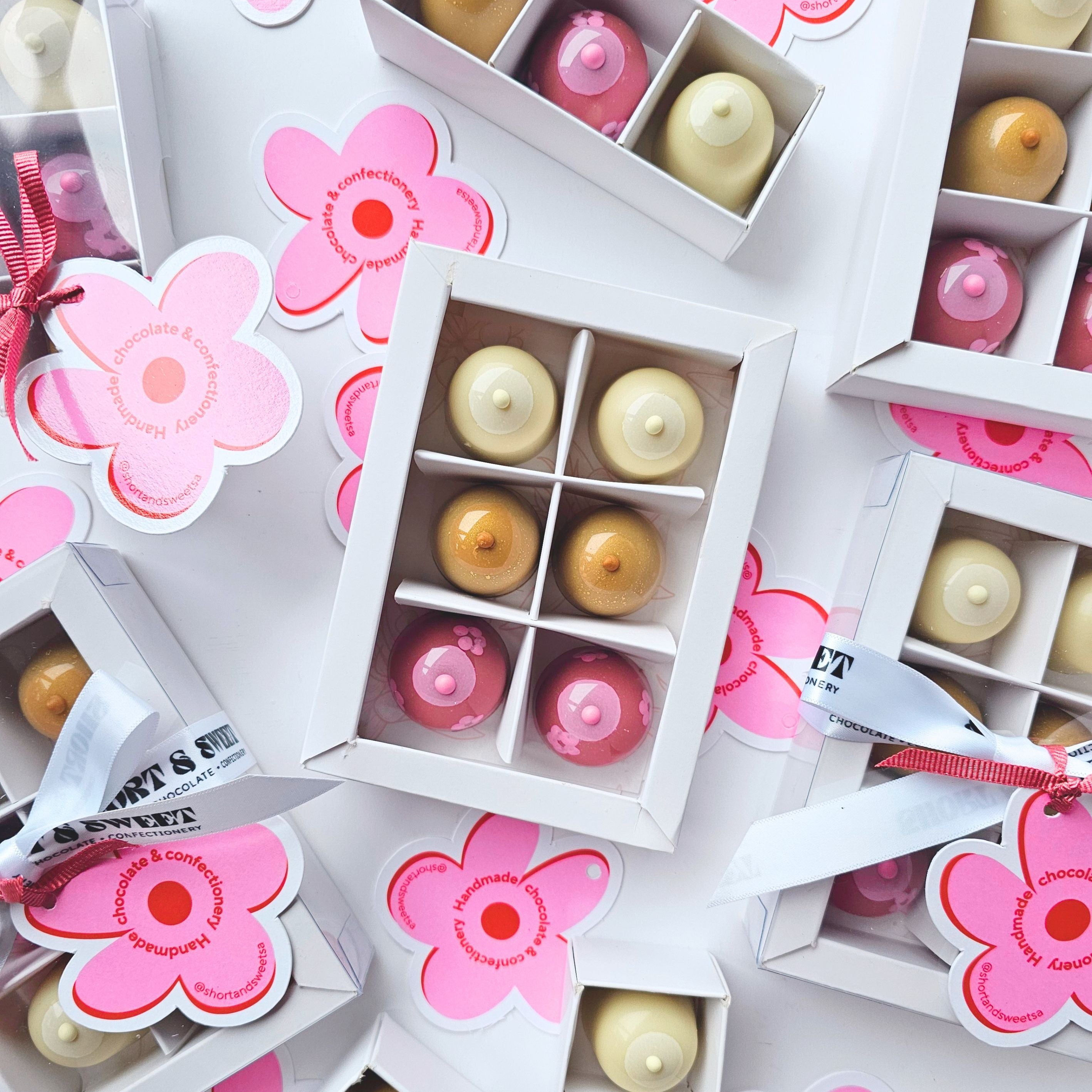 Small boxes with floral designs and colourful chocolates on a white background