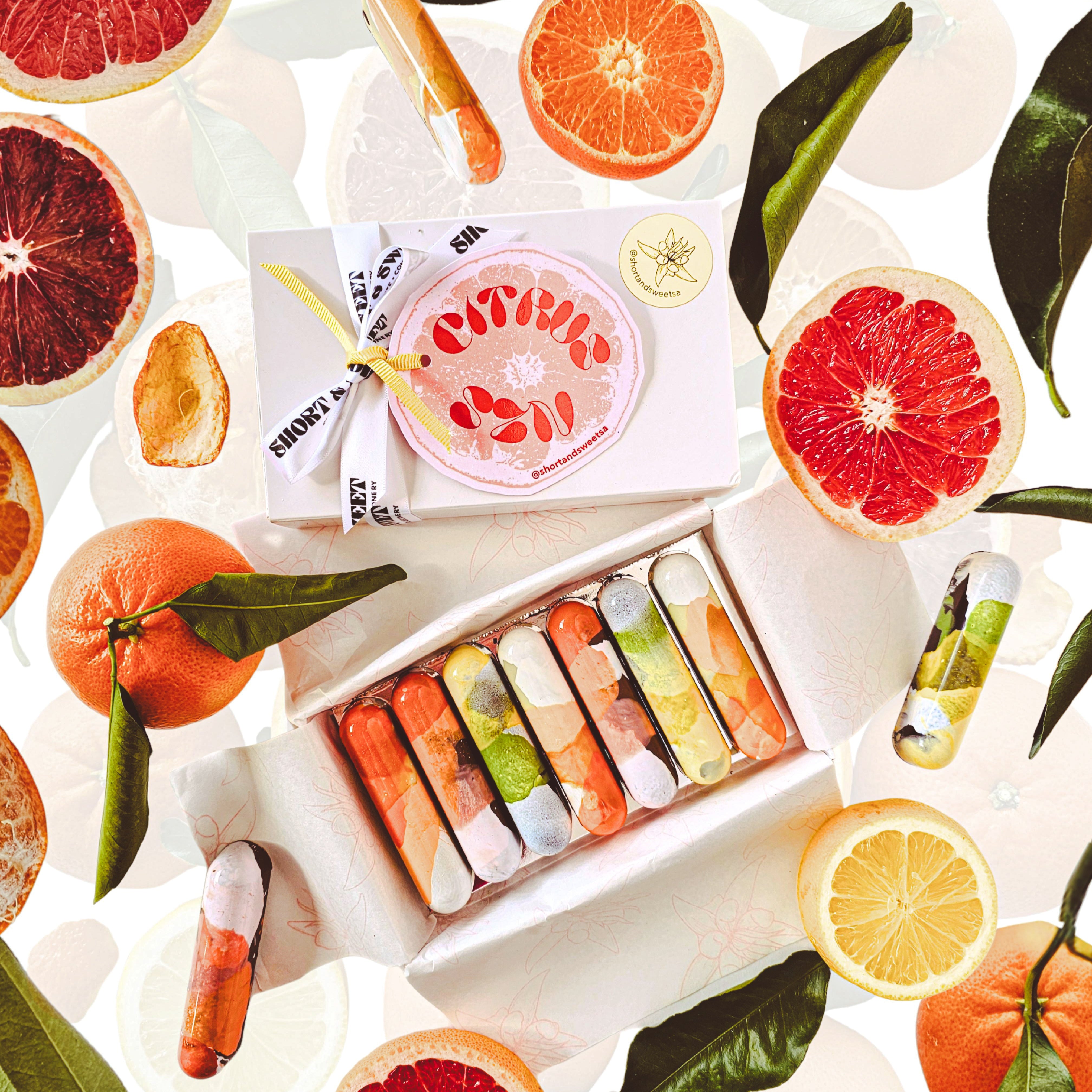 Assorted citrus fruits and a box of colorful items on a white background