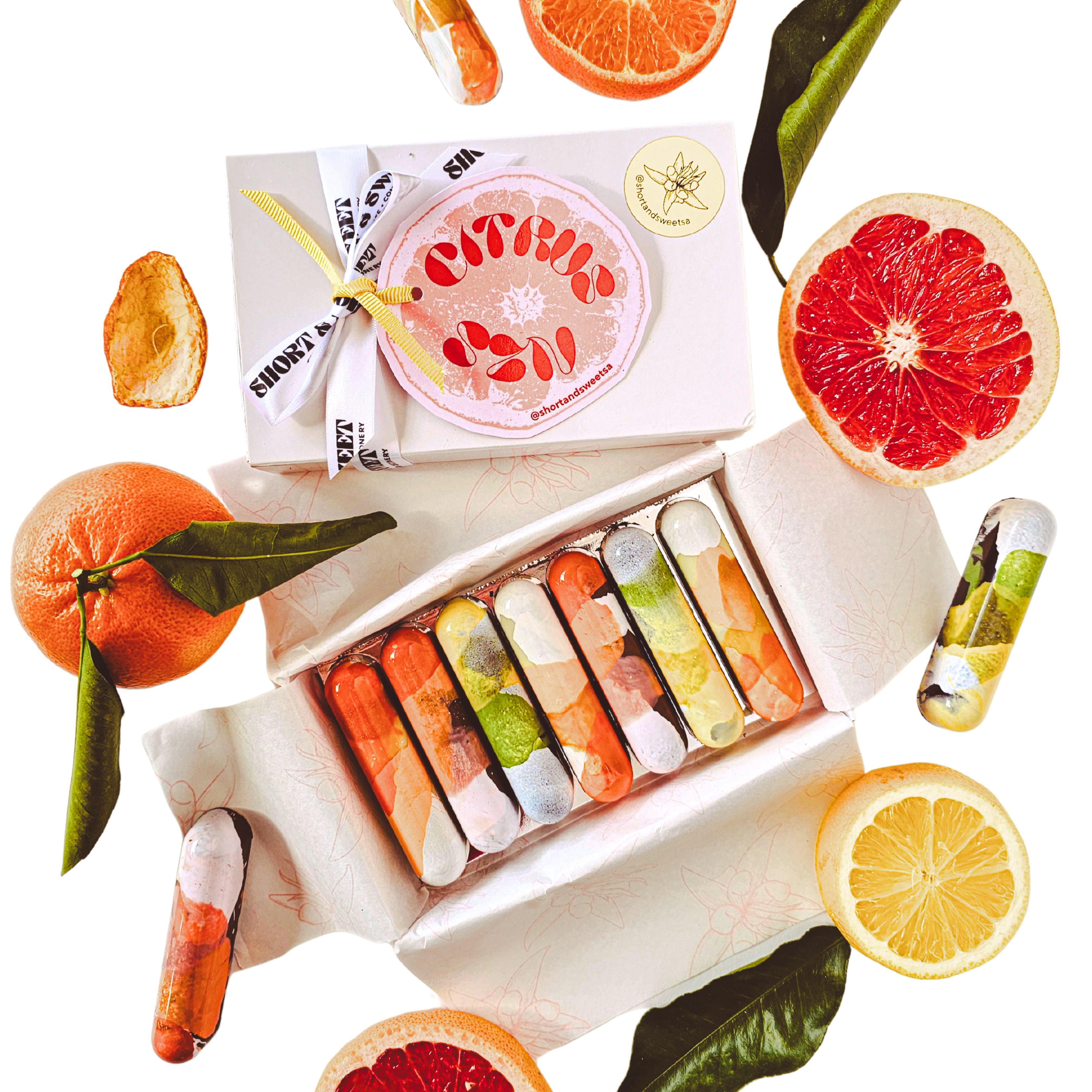 Set of colourful chocolate bars with a box and sliced citrus fruits on a white background