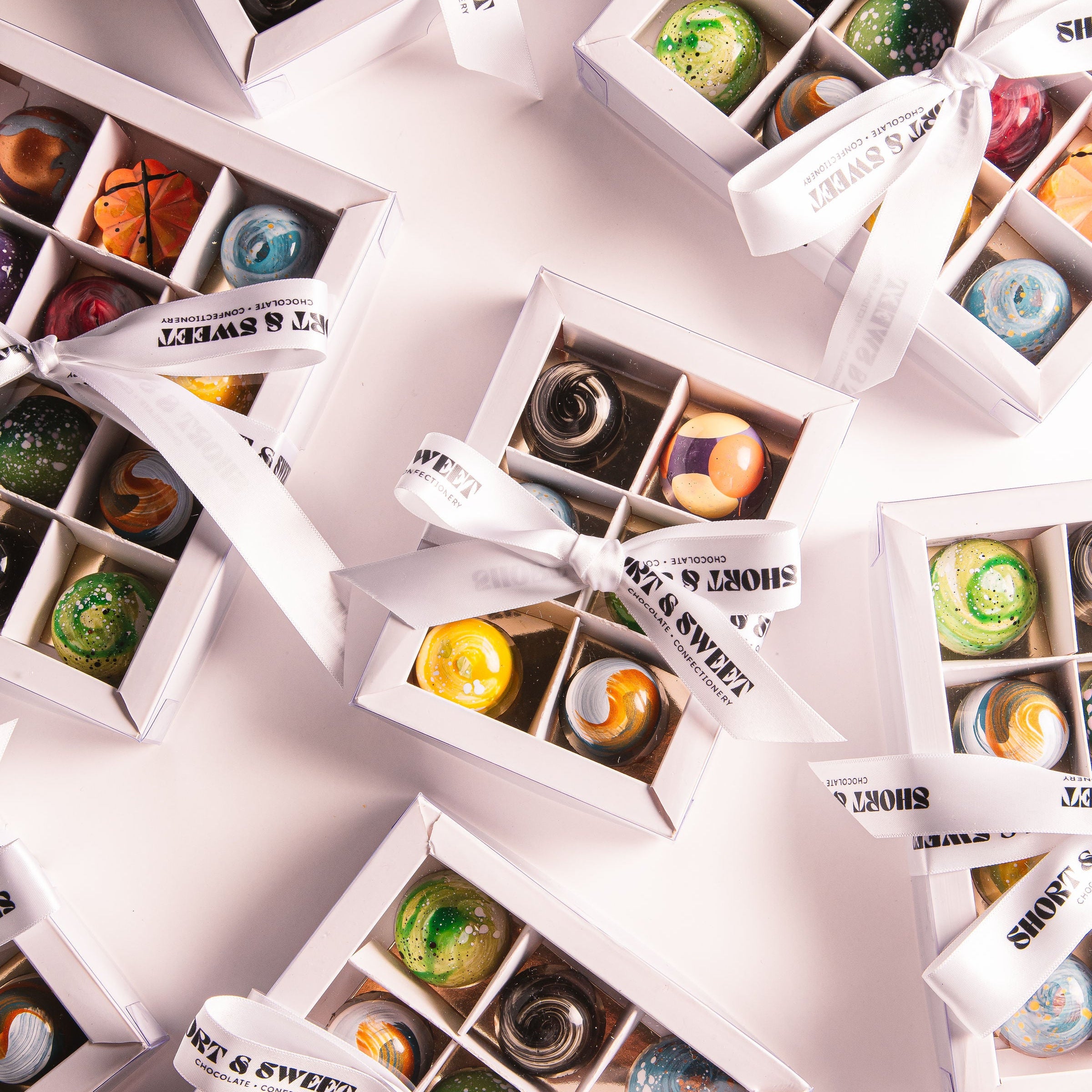 Assorted chocolates in white boxes with visible brand name on a light background