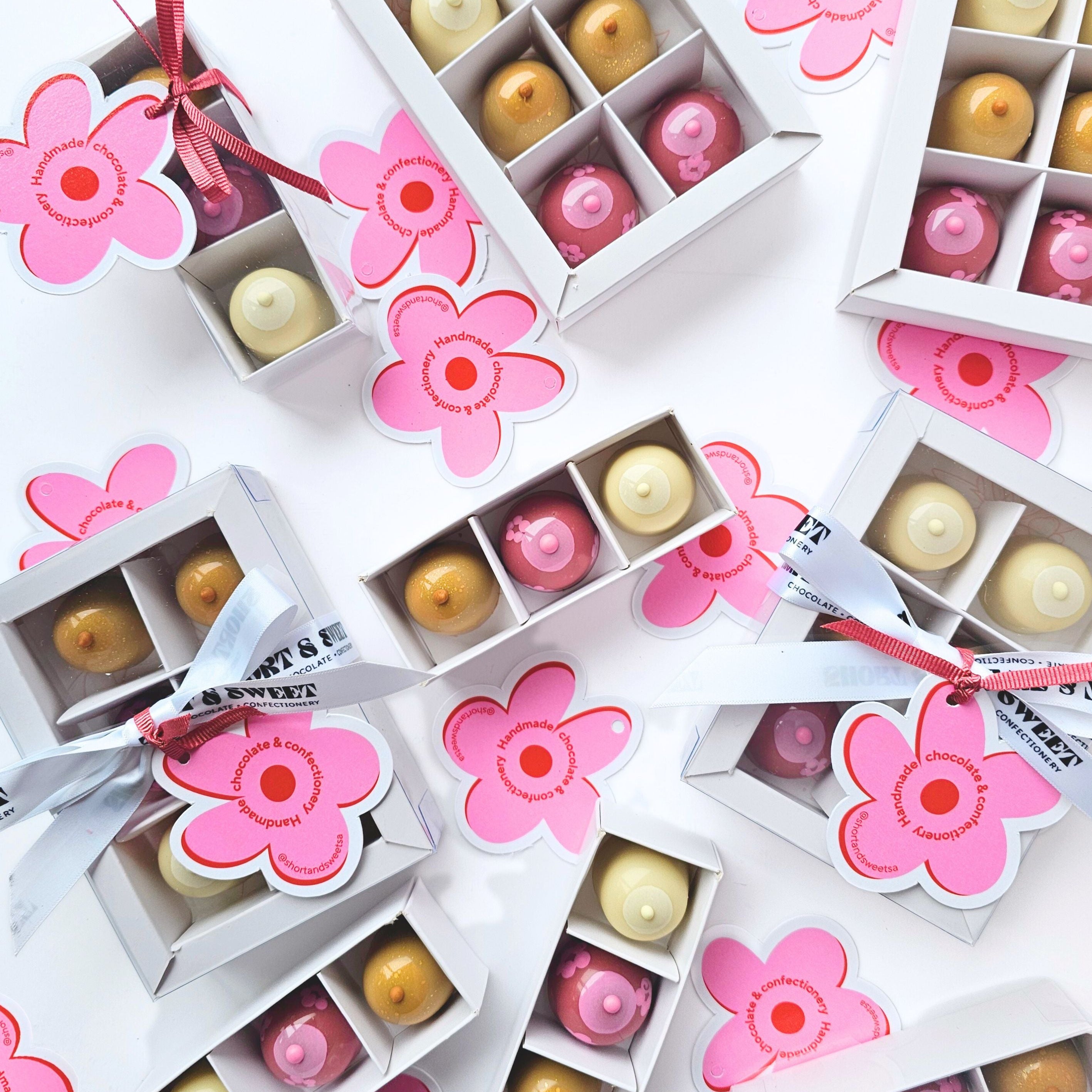Small boxes with floral designs containing round bonbons on a white background